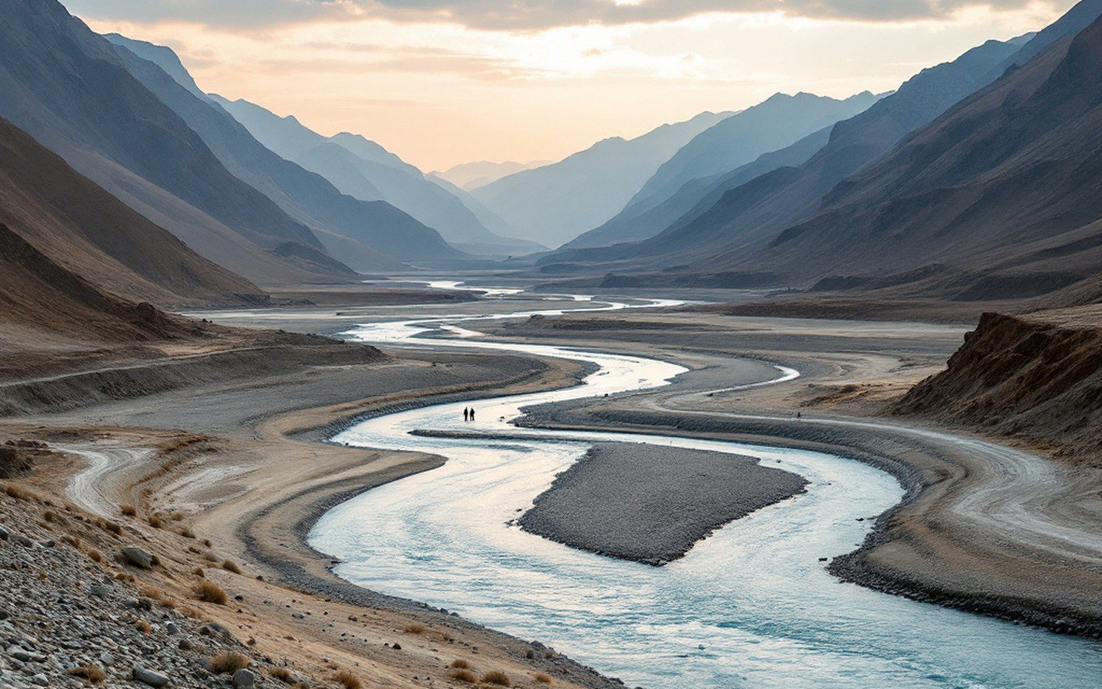 A wide braided river running through a broad dry valley floor with bare mountains on both sides